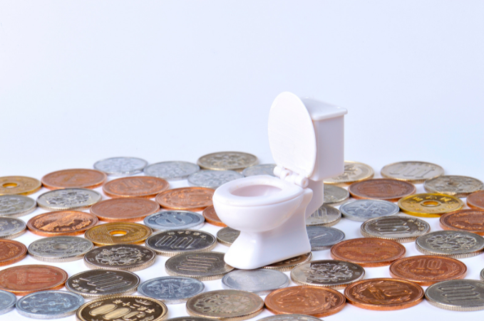 Mini toilet bowl with coins scattered around